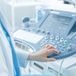 In the Hospital, Obstetrician Pushes Buttons on a Control Panel Before Starting Ultrasound / Sonogram Procedure.